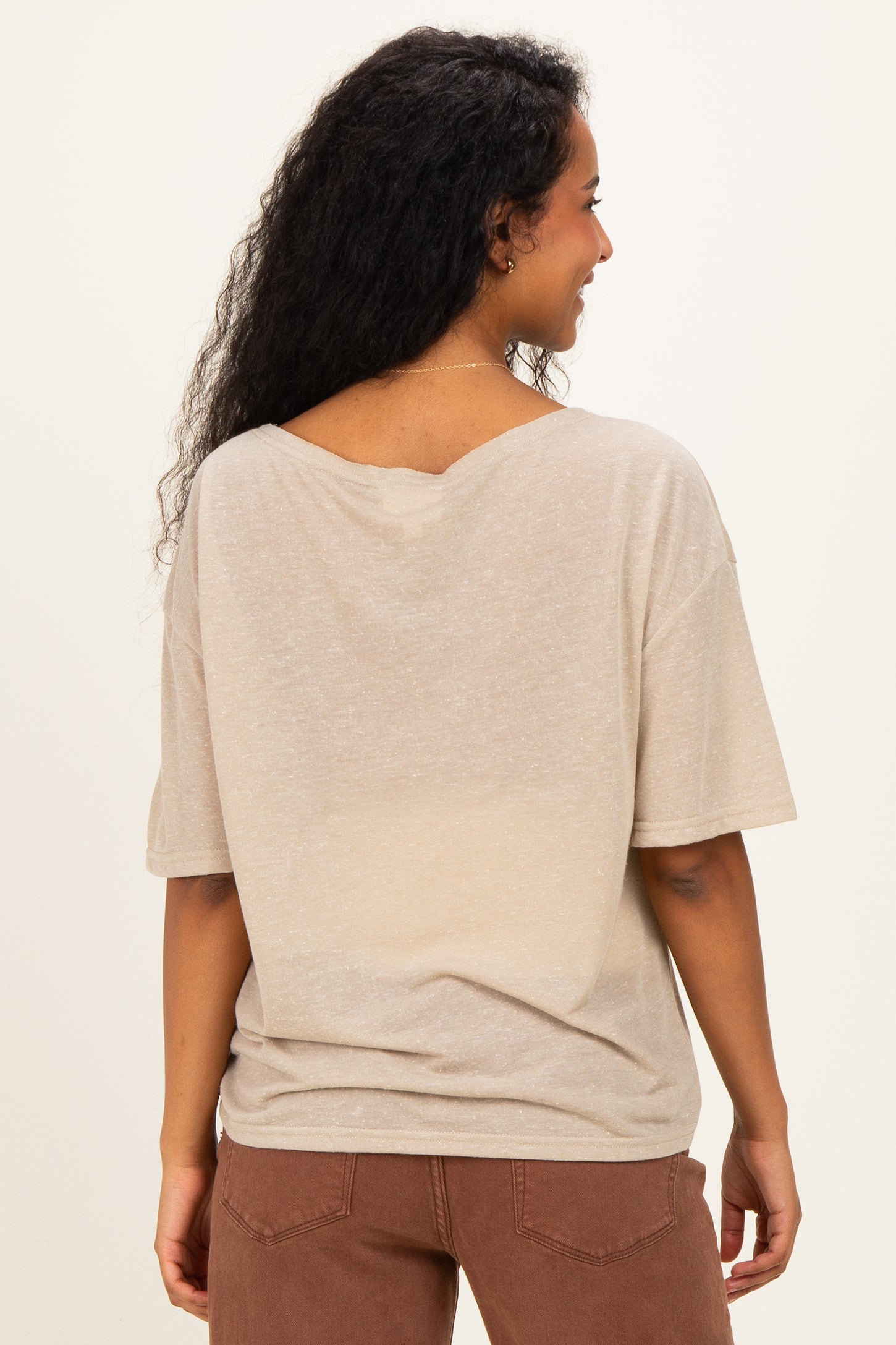 woman wearing a beige maternity top with a relaxed fit and short sleeves, showing a slight v-back detail