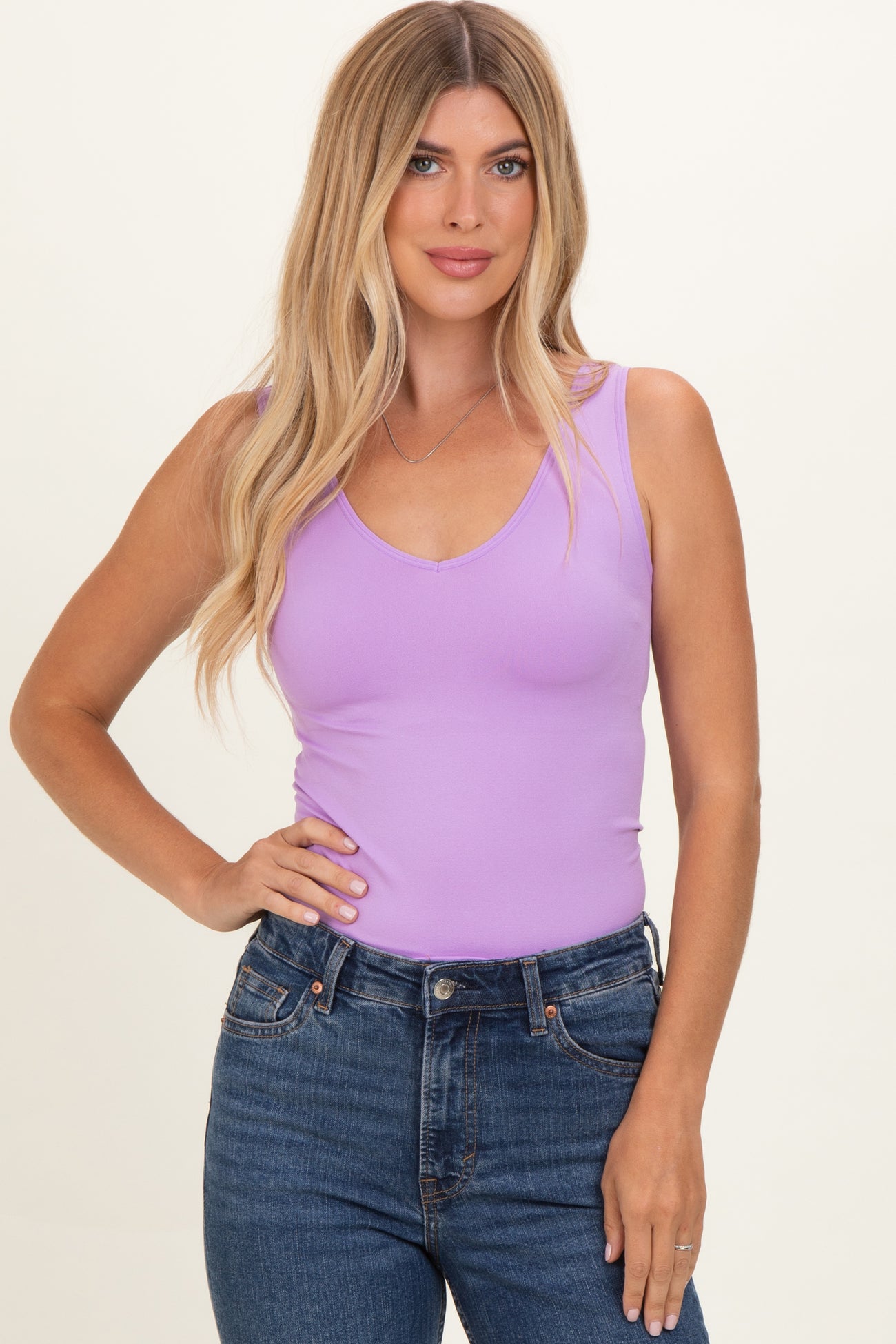 woman wearing a lavender v-neck tank top and high-waisted blue jeans