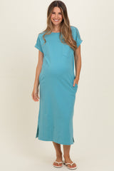 woman wearing a teal maternity dress with short sleeves, pockets, and side slits, showing her baby bump