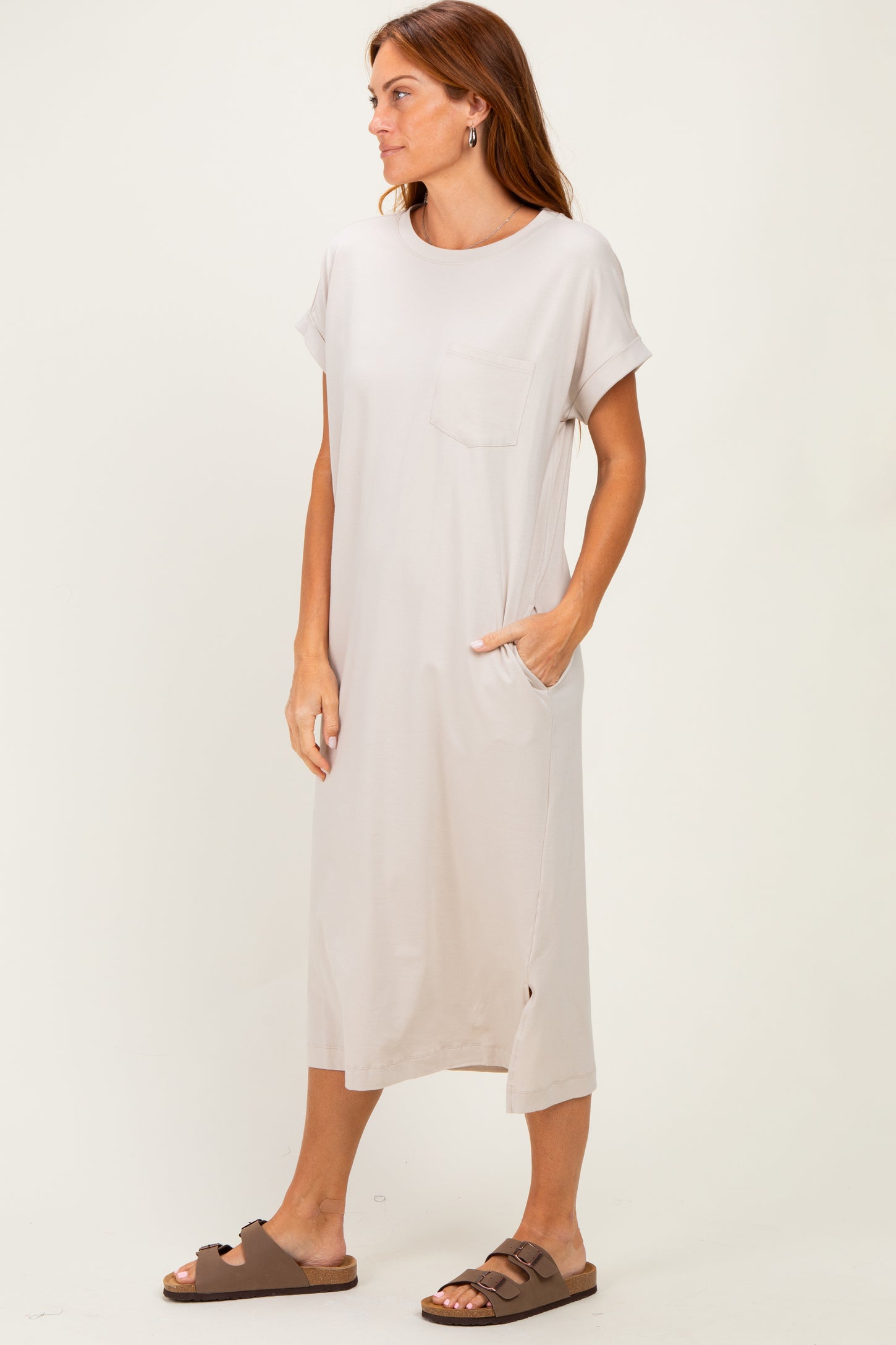 woman wearing a light beige short sleeve midi dress with side pockets and a chest pocket