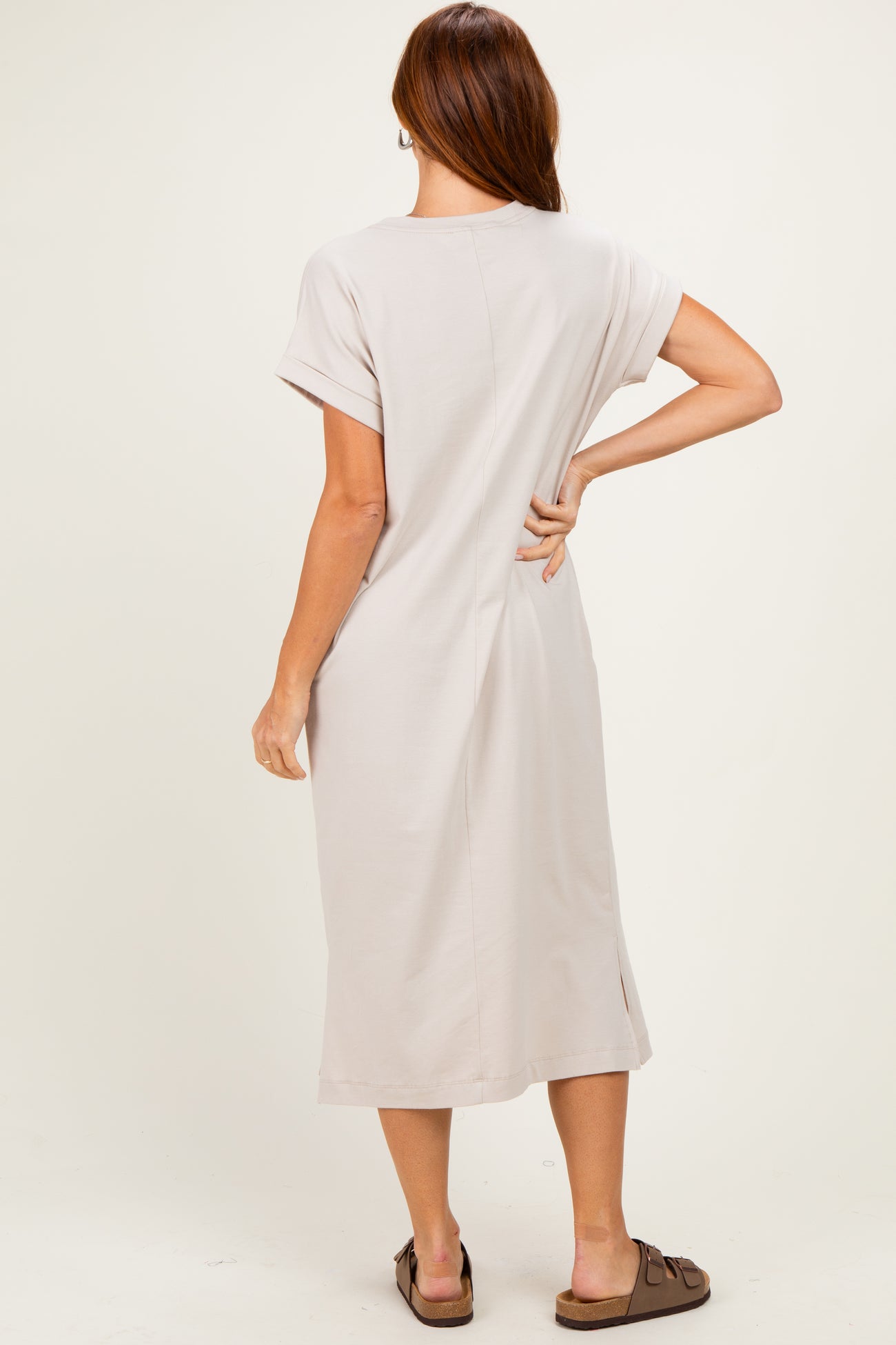 woman wearing a light beige short sleeve midi dress with a relaxed fit and side slits, shown from the back