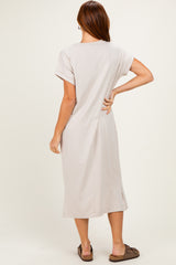 woman wearing a light beige short sleeve midi dress with a relaxed fit and side slits, shown from the back