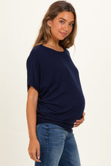 woman wearing a navy blue short sleeve maternity top and holding her baby bump