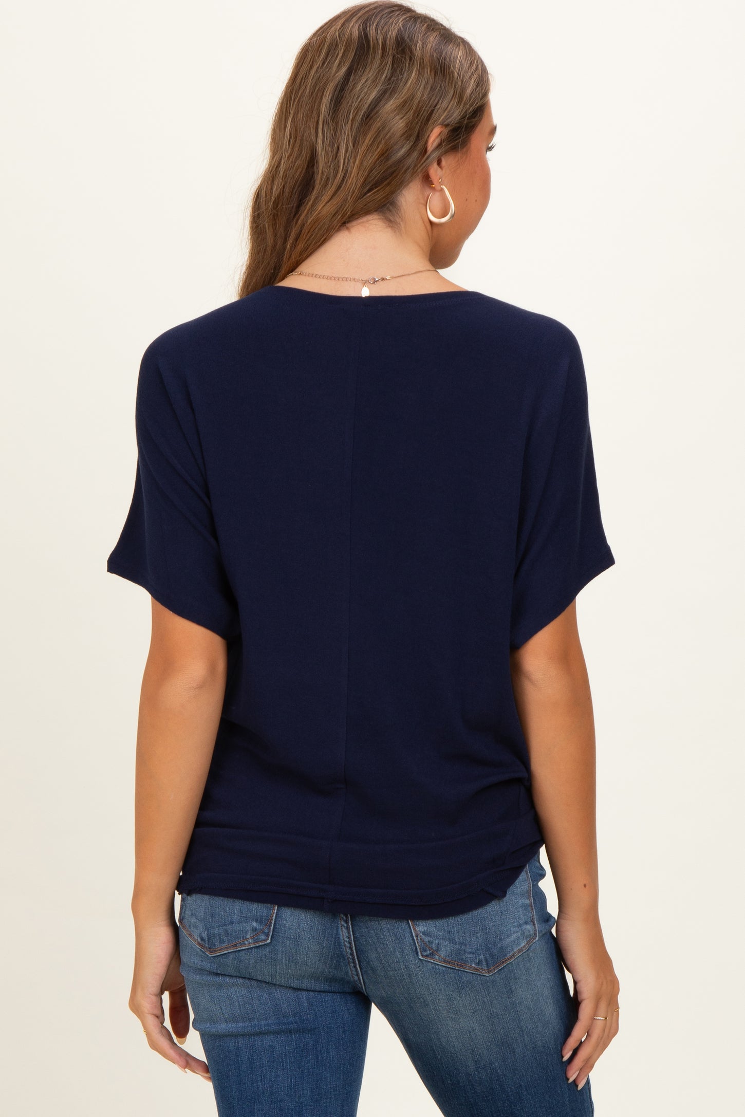 woman wearing a navy blue maternity top with short sleeves, view is from the back showing a relaxed fit