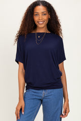 woman wearing a navy blue short sleeve top with relaxed fit and layered necklaces, paired with blue jeans