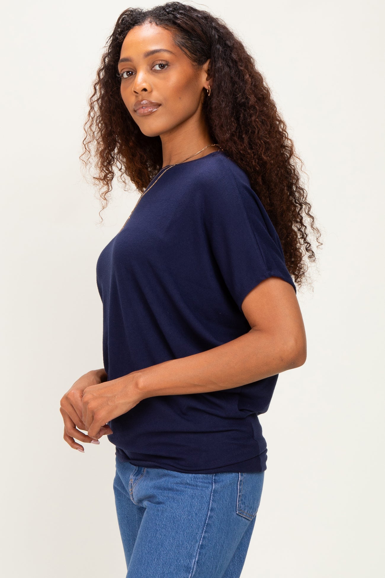 woman wearing a navy blue oversized t-shirt with short sleeves and standing sideways in fitted jeans