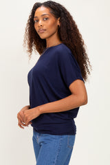 woman wearing a navy blue oversized t-shirt with short sleeves and standing sideways in fitted jeans