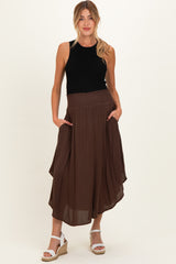 woman wearing a black sleeveless top and a brown maternity skirt with an asymmetric hem and pockets