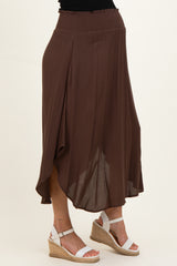 woman wearing a brown maternity skirt with a smocked waist and a flowy design, styled with white wedge sandals