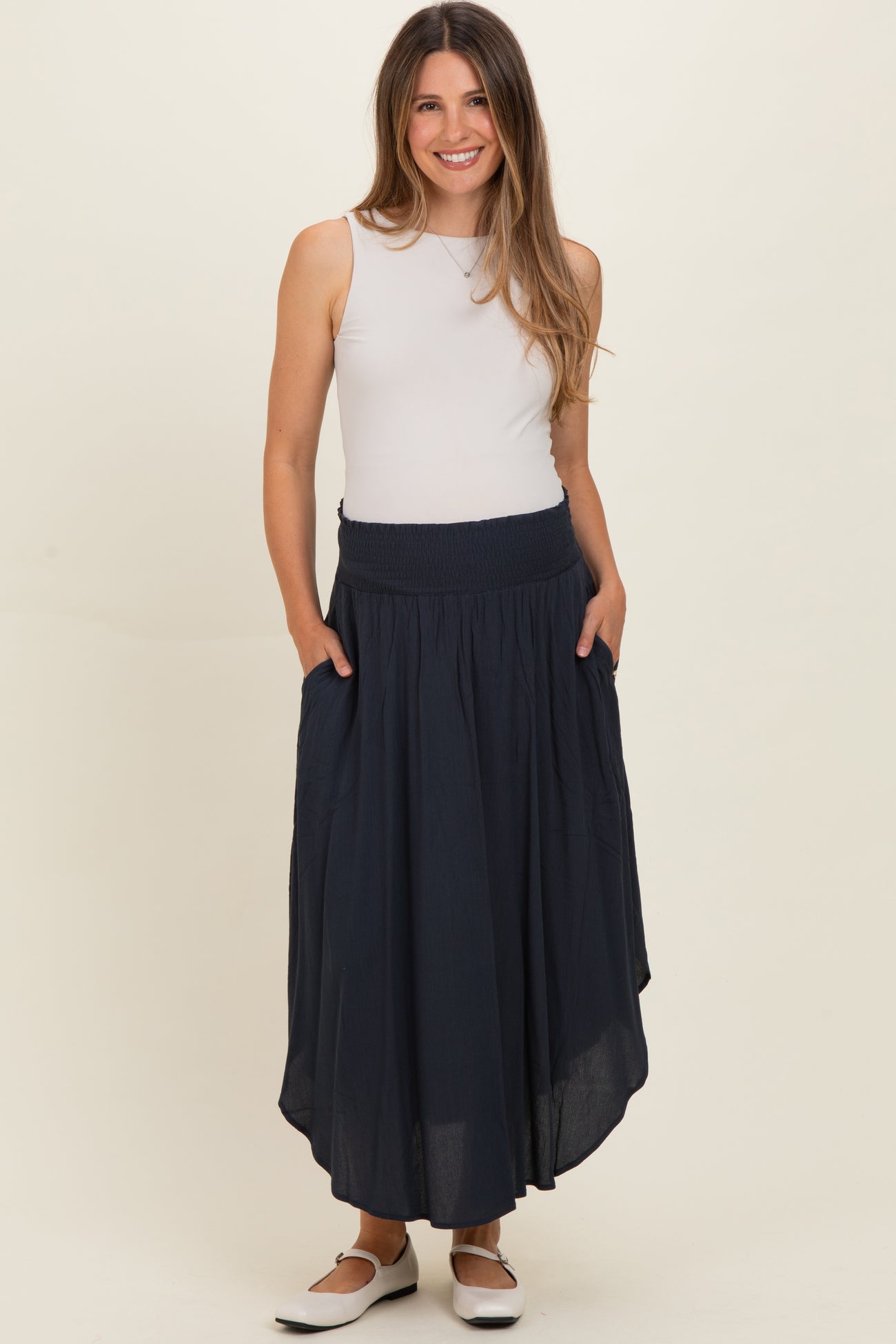 woman wearing a navy blue maternity maxi skirt with pockets and a smocked waistband
