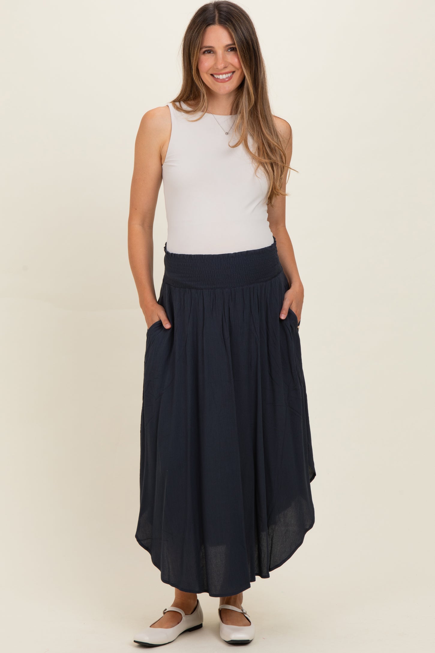 woman wearing a navy blue maternity maxi skirt with pockets and a smocked waistband