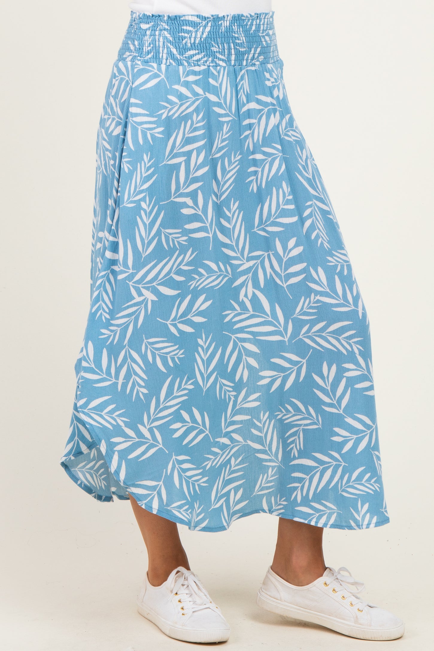woman wearing a blue floral print maxi skirt with an elastic waistband and white sneakers