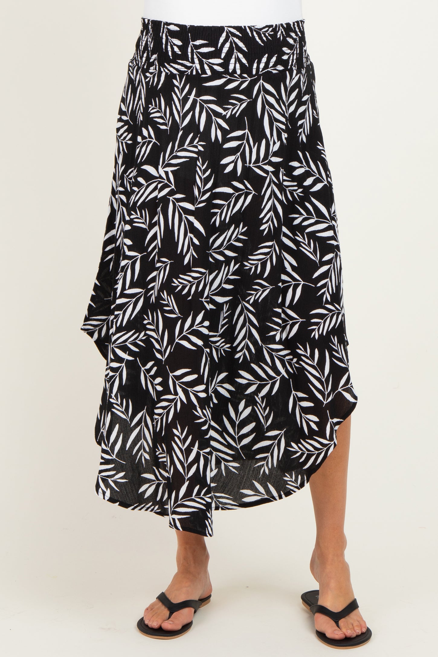 maternity wear black and white leaf print wrap skirt with an asymmetrical hem, model wearing it with flip-flops