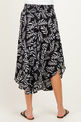 woman wearing a black midi maternity skirt with white leaf print and asymmetrical hem, showing her back