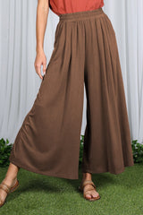 woman wearing brown wide-leg pants with an elastic waistband and styled with a rust-colored top