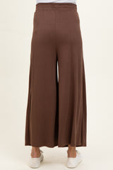 woman wearing brown wide-leg maternity pants, showing the back view and styled with white sneakers