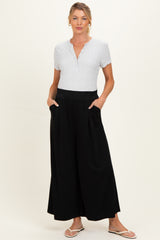 woman wearing a light gray short sleeve henley maternity top and black wide-leg maternity pants with pockets