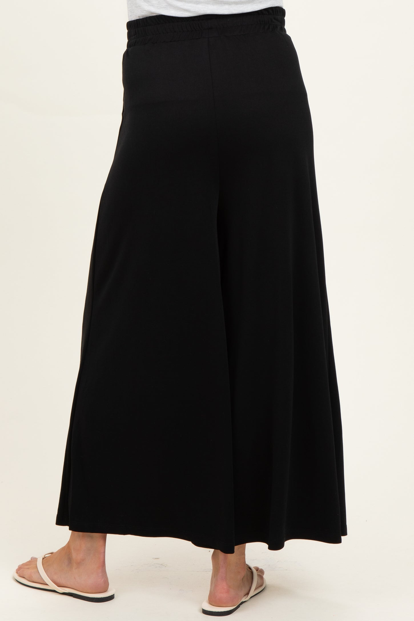 woman wearing black maternity wide-leg pants, showing the back view and comfortable elastic waistband