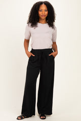 woman wearing a light gray short sleeve top and black wide-leg pants with pockets