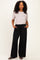 woman wearing a light gray short sleeve top and black wide-leg pants with pockets