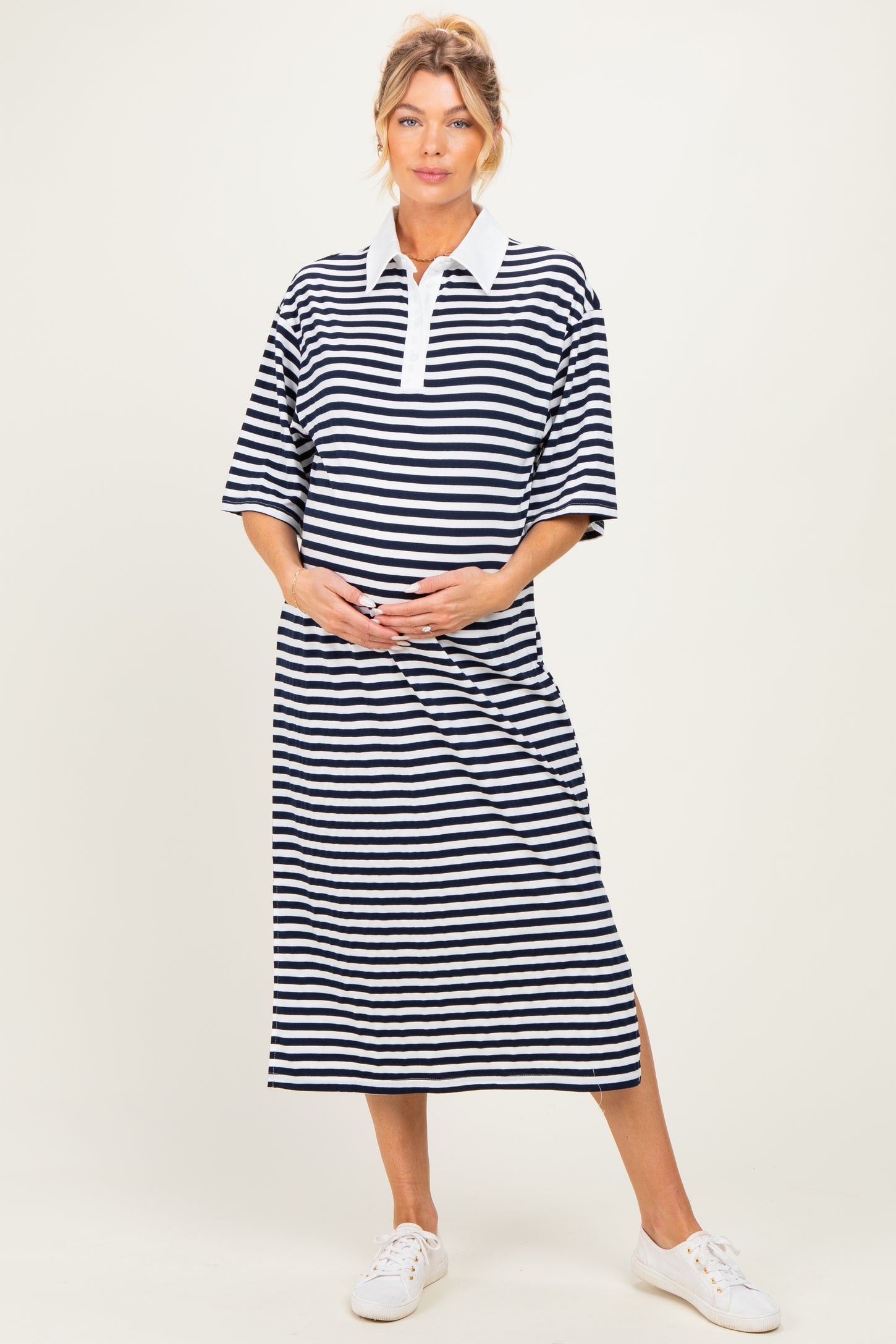 woman wearing a navy and white striped maternity polo dress and holding her baby bump