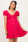 woman wearing a hot pink short puff sleeve maternity dress with buttons and ruffled hem, showing her baby bump