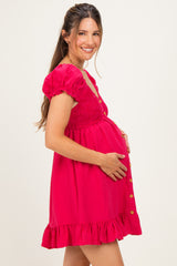 woman wearing a hot pink maternity dress with puffy sleeves, smocked bodice, and button details, showing her baby bump