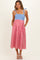 woman wearing a blue and red gingham maternity dress with adjustable straps and pockets