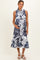 woman wearing a navy and white floral maternity dress with a button front and ruffle hem, holding her baby bump