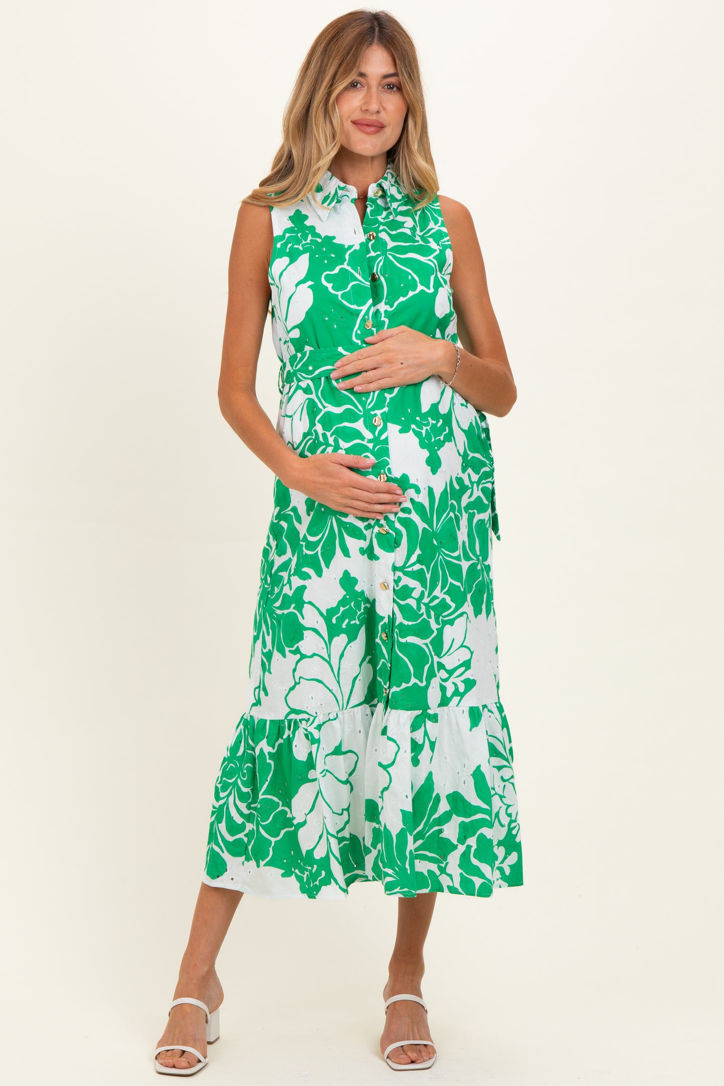 woman wearing a green floral maternity dress with a button-down front and tiered skirt, showing her baby bump