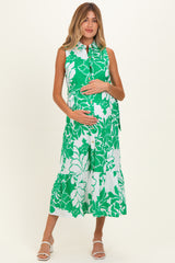 woman wearing a green floral maternity dress with a button-down front and tiered skirt, showing her baby bump