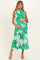 woman wearing a green floral maternity dress with a button-down front and tiered skirt, showing her baby bump