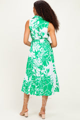 woman wearing a sleeveless green and white floral dress with a tiered hem and tie waist, seen from the back