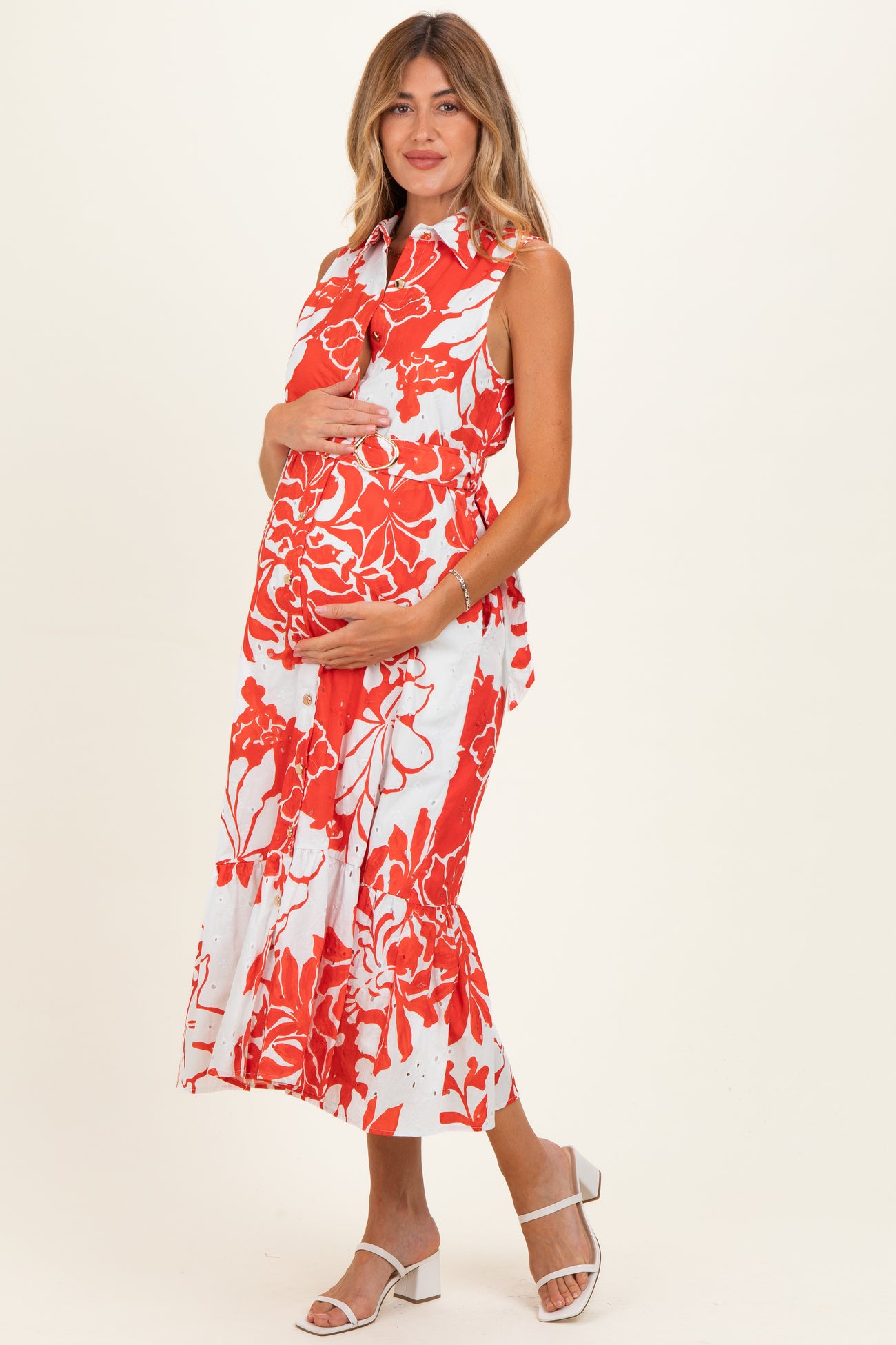 woman wearing a red and white floral maternity dress and holding her baby bump