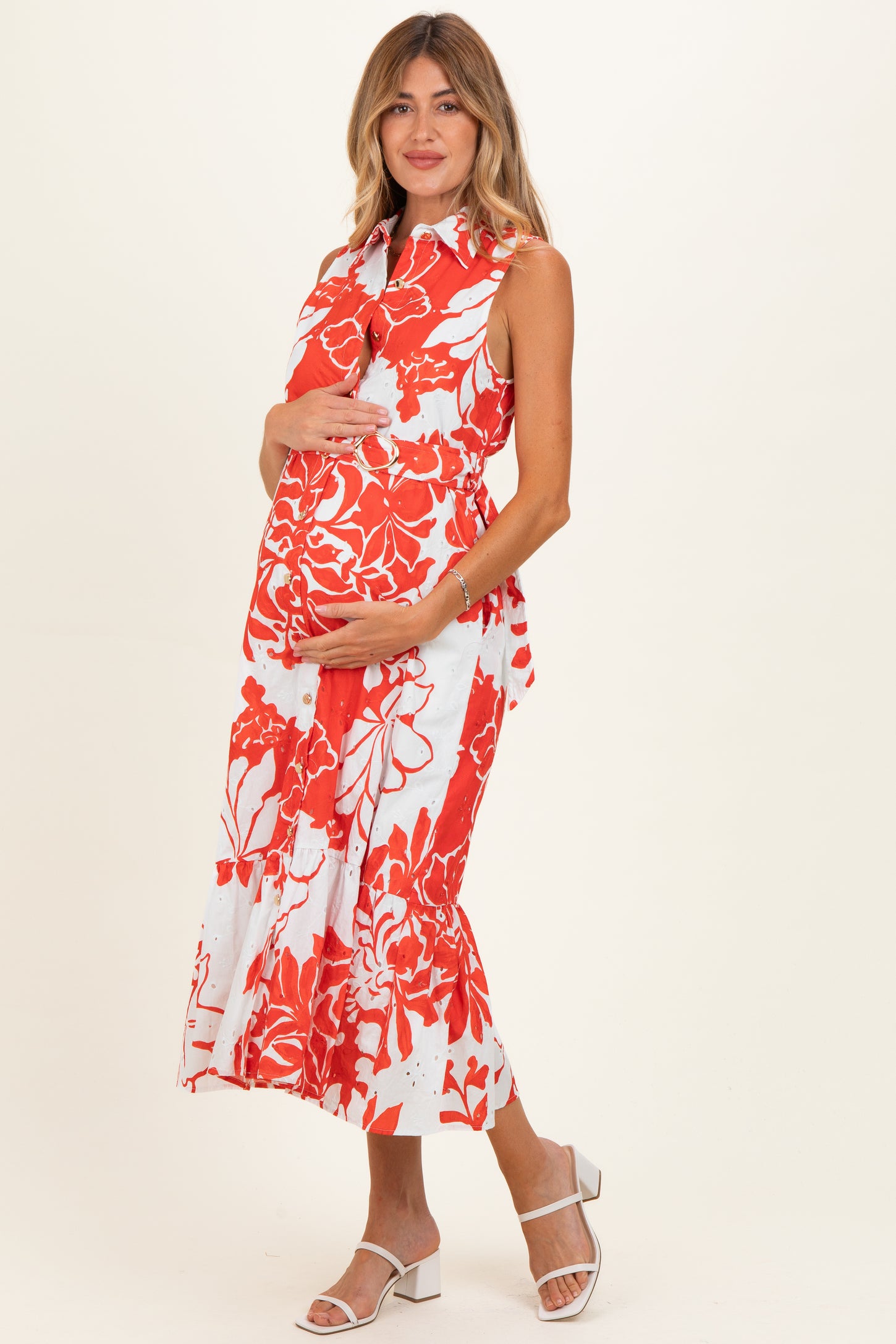 woman wearing a red and white floral maternity dress and holding her baby bump