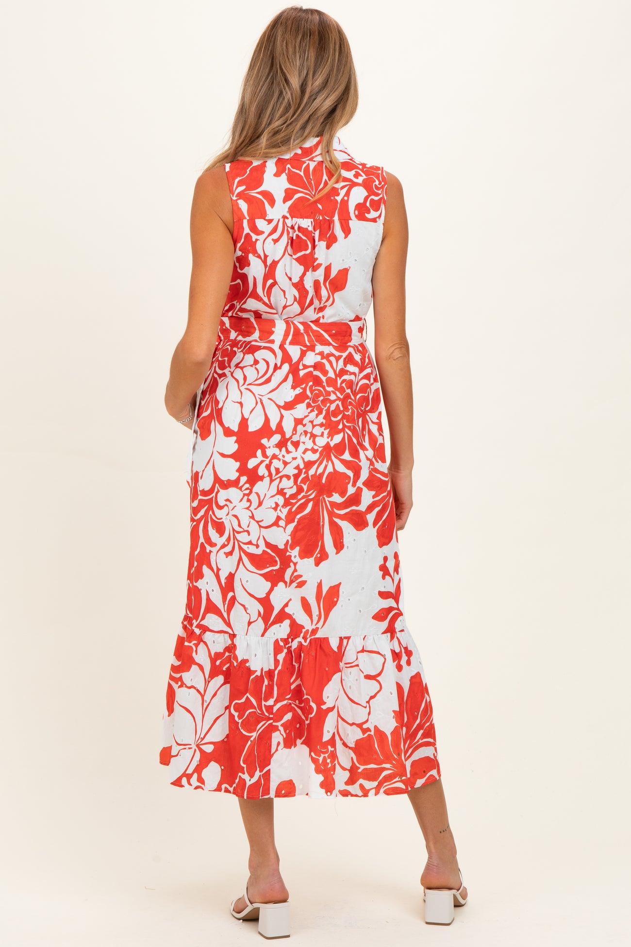 woman wearing a sleeveless floral maternity maxi dress in red and white, showing a flowing silhouette and back design