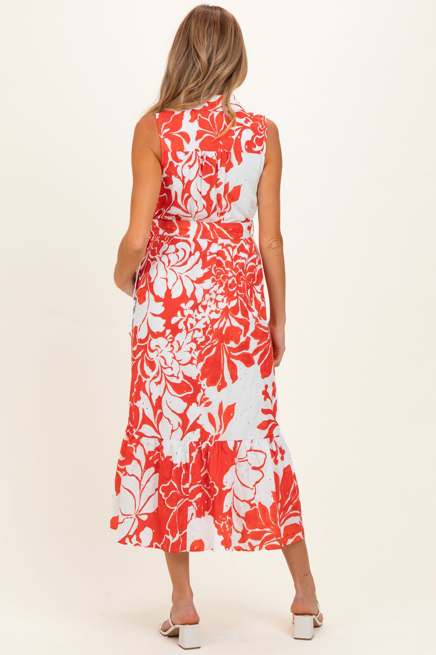 woman wearing a sleeveless floral maternity maxi dress in red and white, showing a flowing silhouette and back design