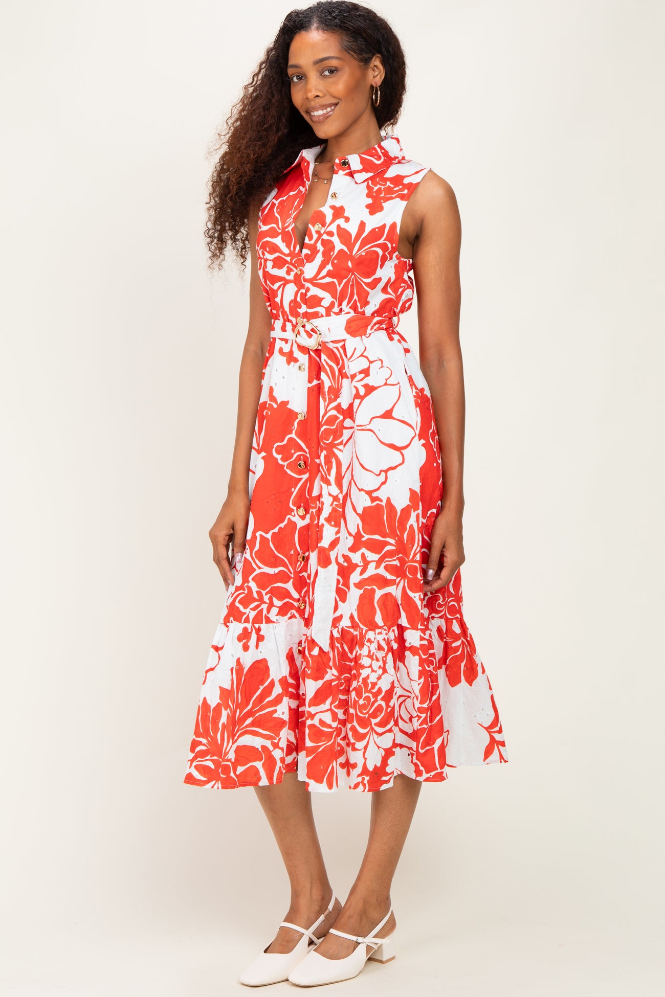 woman wearing a sleeveless red and white floral midi dress with a belt and a ruffled hem