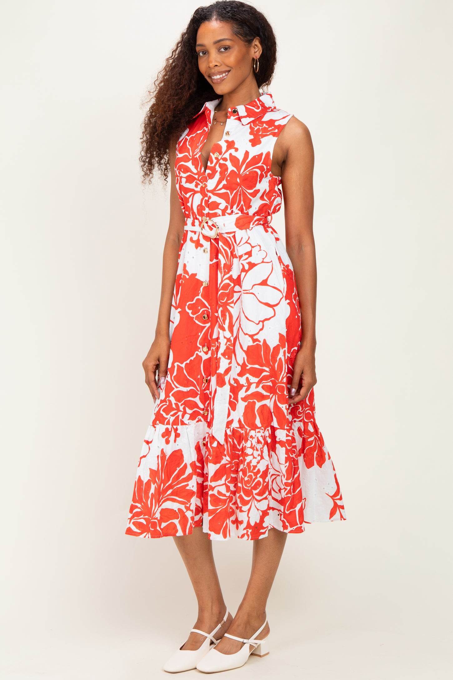 woman wearing a sleeveless red and white floral midi dress with a belt and a ruffled hem
