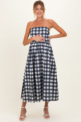 woman wearing a navy and white gingham strapless maternity dress with a fitted bodice and a flared skirt, holding her baby bump