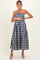 woman wearing a navy and white gingham strapless maternity dress with a fitted bodice and a flared skirt, holding her baby bump