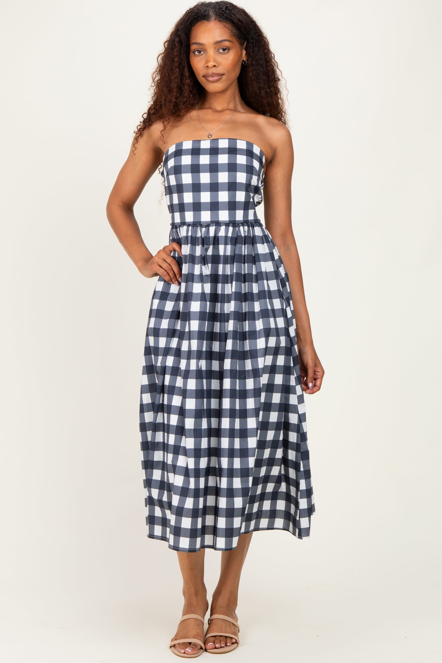 woman wearing a navy and white checkered strapless midi dress with a fitted bodice and flowy skirt