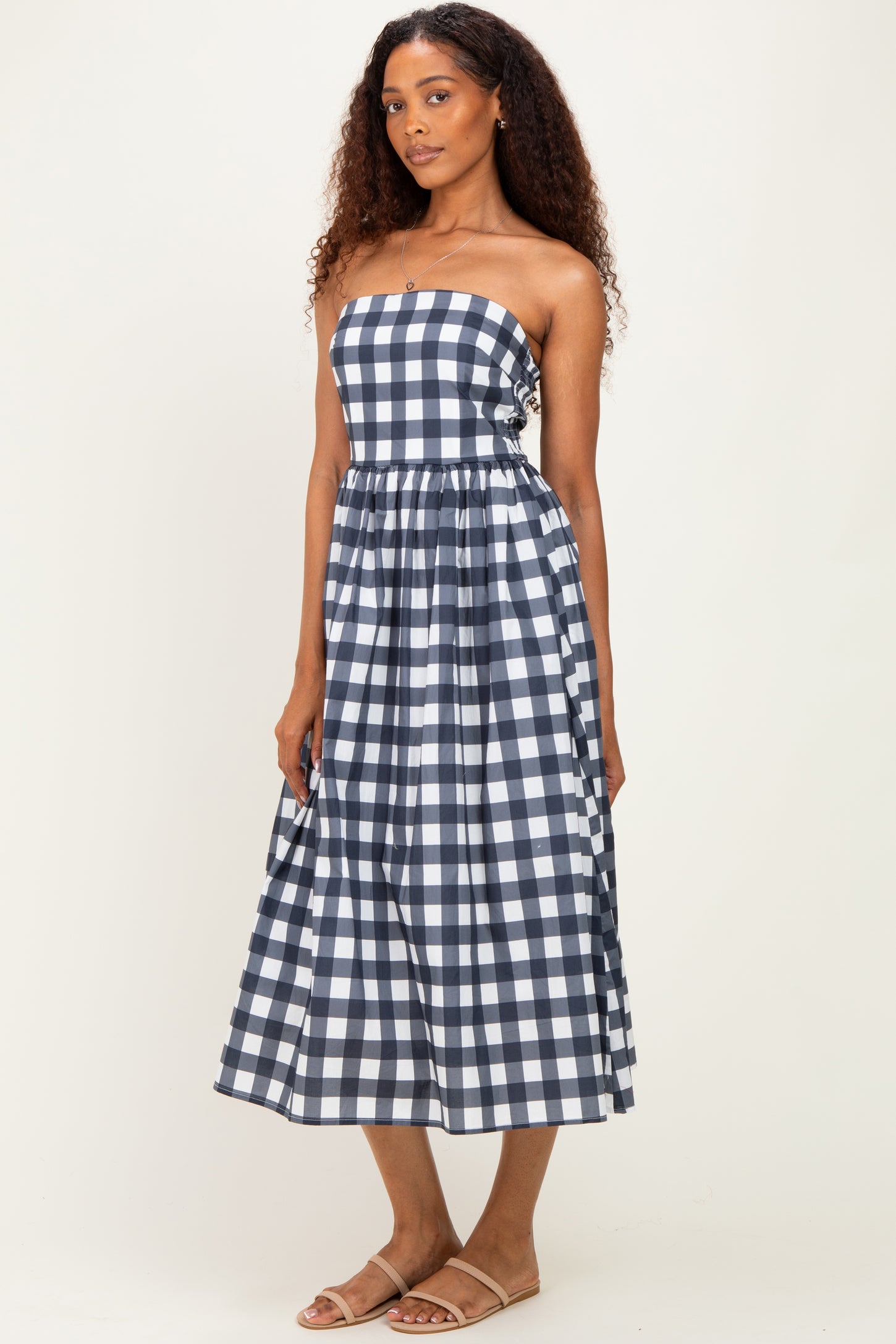 woman wearing a navy and white checkered strapless midi dress with a cinched waist and flowing skirt