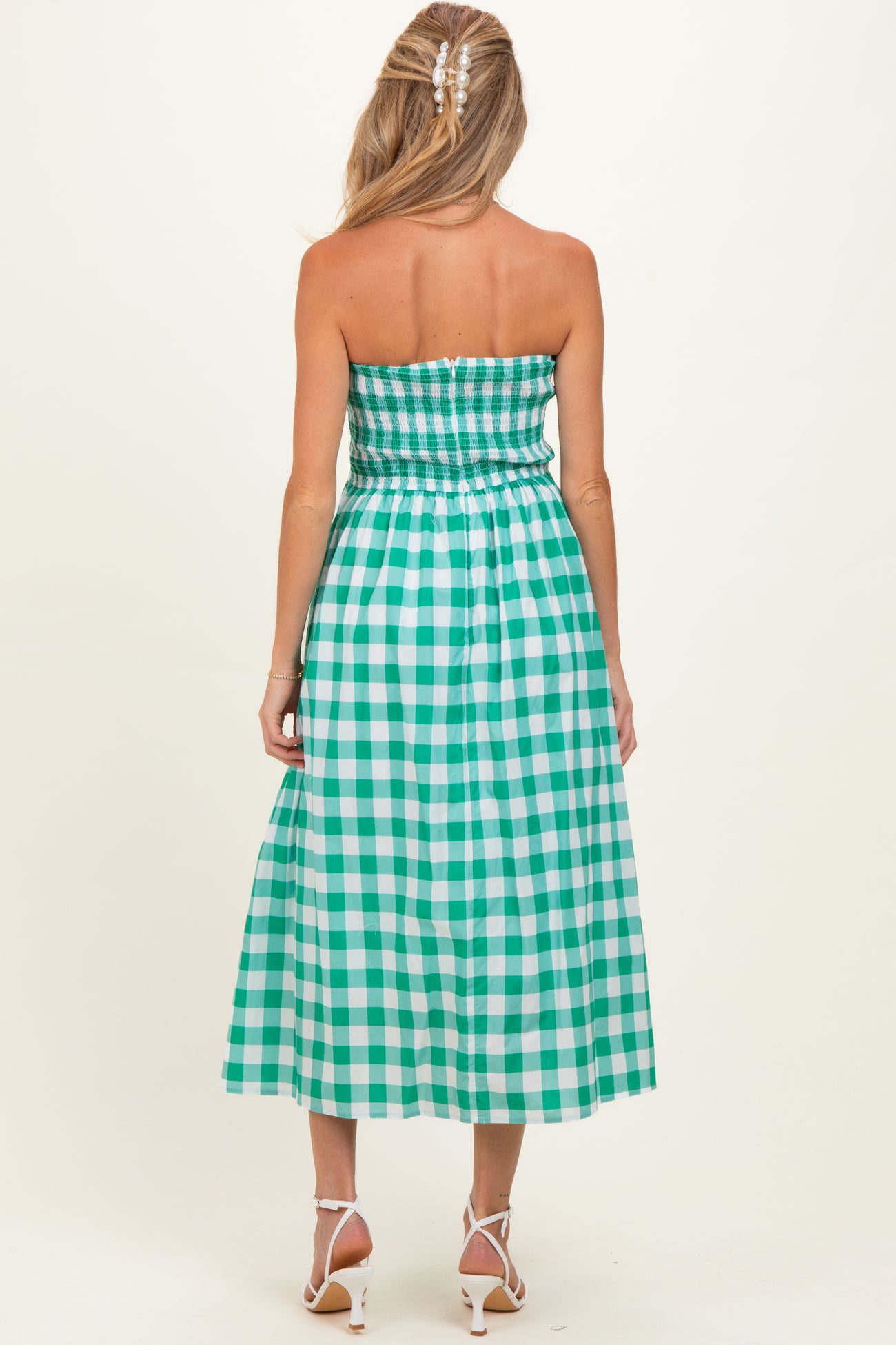 woman wearing a green and white checkered strapless maternity dress with a smocked bodice and flowy skirt
