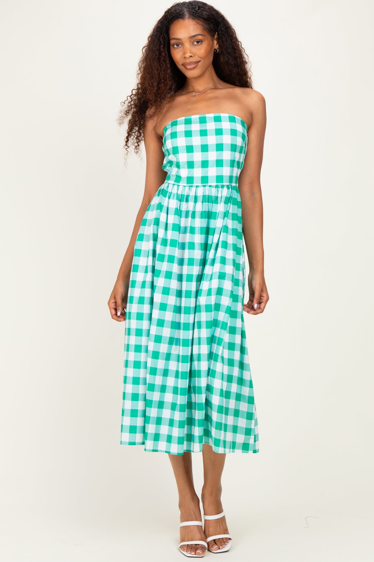 woman wearing a strapless green and white gingham midi dress with a cinched waist and flowy skirt