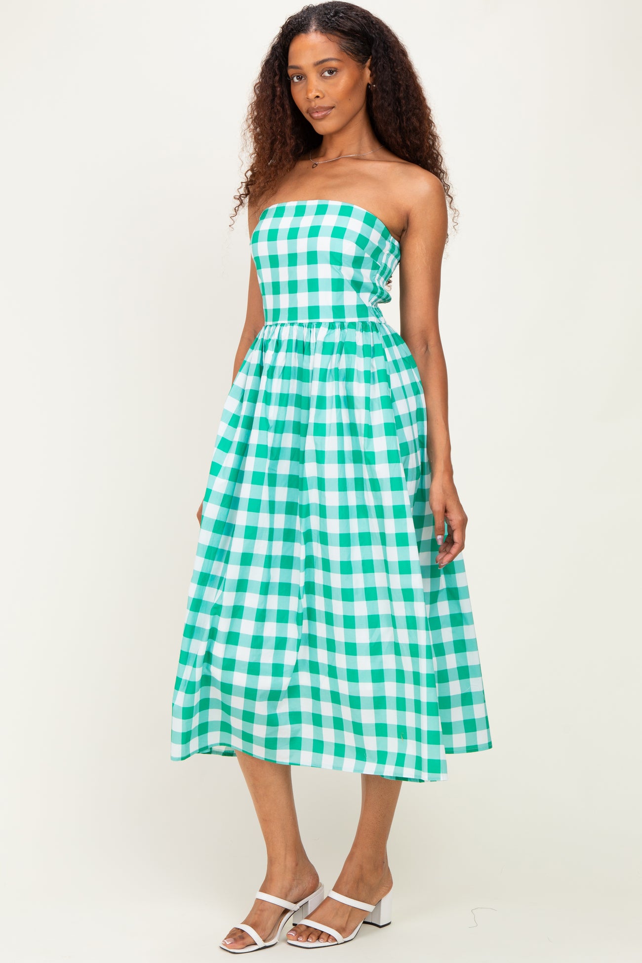 woman wearing a green and white gingham strapless midi dress with a fitted bodice and flowy skirt