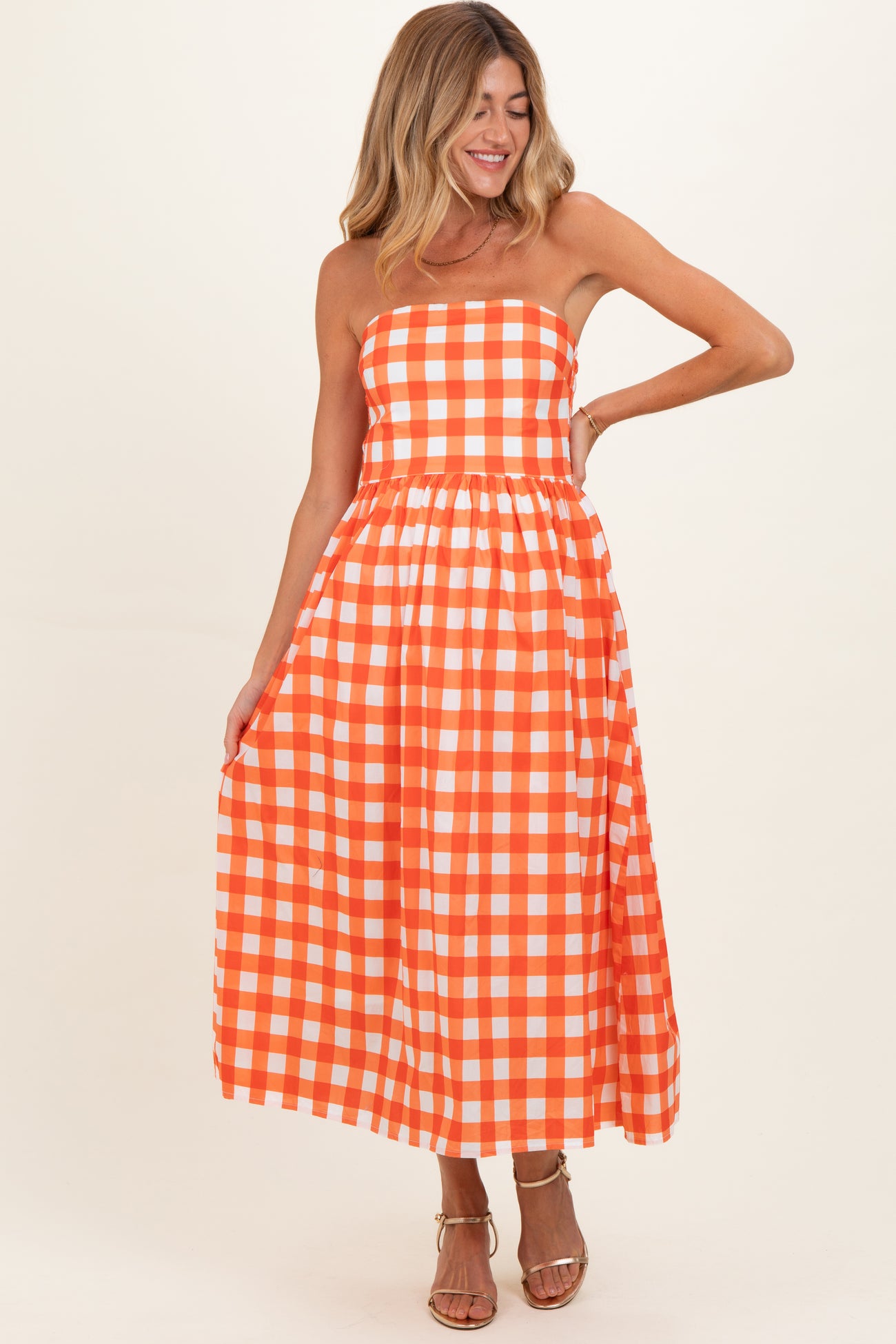 woman wearing an orange and white checkered strapless maternity dress with a flowing skirt