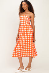 woman wearing a strapless orange and white gingham midi dress with a fitted bodice and flared skirt