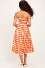 woman wearing an orange and white checkered strapless midi dress, showing the back view and curly hair