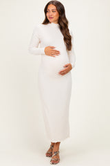 woman wearing a cream long sleeve maternity dress and holding her baby bump
